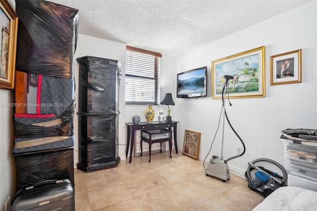 interior space featuring a textured ceiling, light tile patterned floors, and baseboards