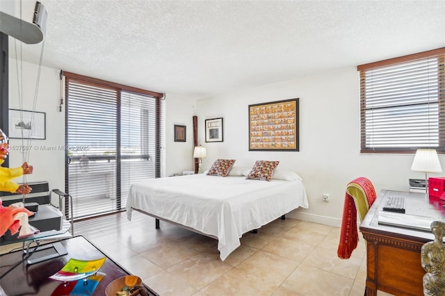 bedroom featuring baseboards, a textured ceiling, and light tile patterned floors