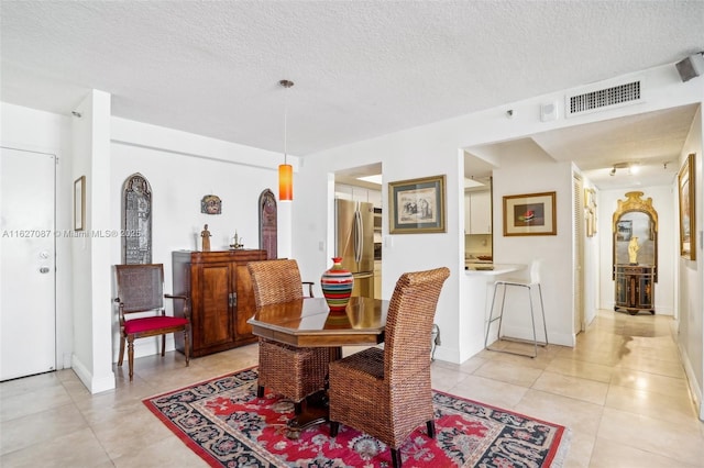 dining space featuring baseboards, a textured ceiling, visible vents, and light tile patterned floors