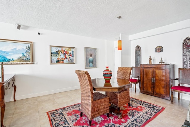 dining space with baseboards, a textured ceiling, and light tile patterned floors