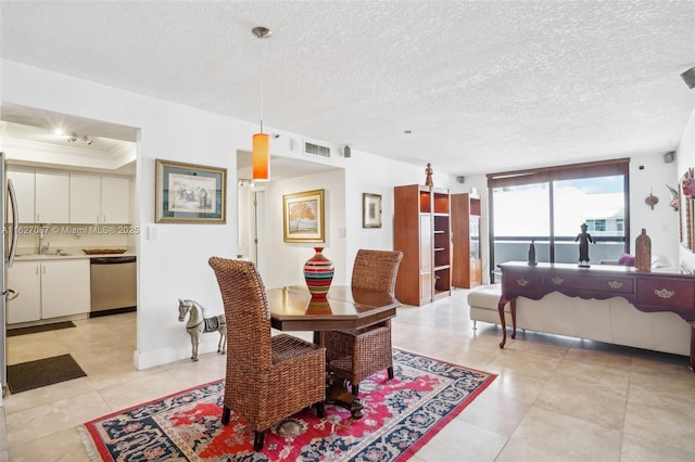 dining space featuring a textured ceiling, ornamental molding, a raised ceiling, and visible vents