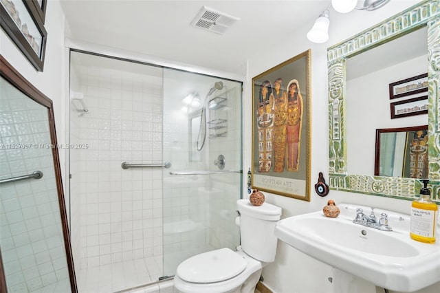 bathroom featuring toilet, a shower with door, and sink