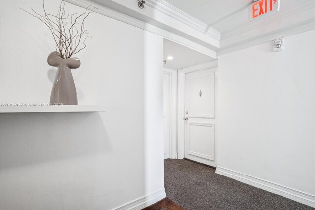 hall with dark colored carpet and crown molding