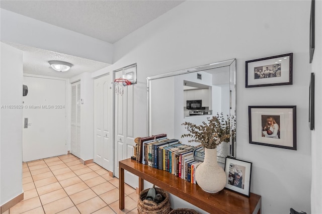 corridor with a textured ceiling and light tile patterned floors