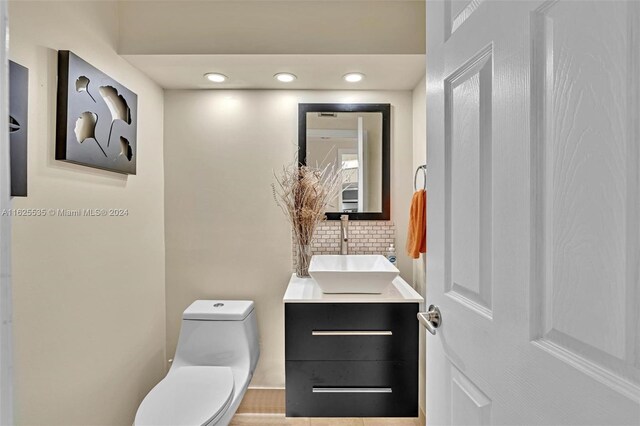 bathroom with vanity, decorative backsplash, and toilet