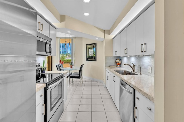 kitchen with appliances with stainless steel finishes, light tile patterned floors, white cabinets, and sink