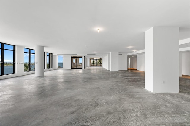 unfurnished living room with a water view and concrete flooring