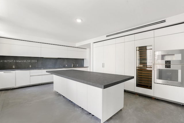 kitchen featuring white cabinets, tasteful backsplash, a center island, and oven