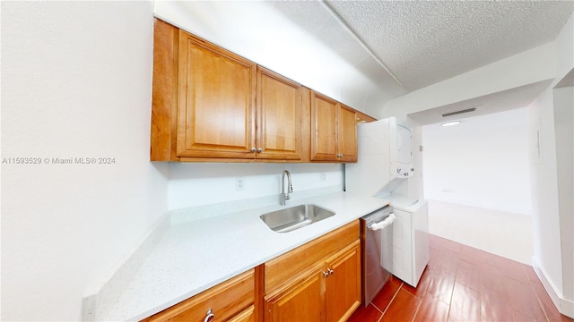 kitchen with dark tile patterned floors, dishwasher, sink, and a textured ceiling