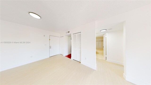 unfurnished bedroom with ensuite bath and light wood-type flooring