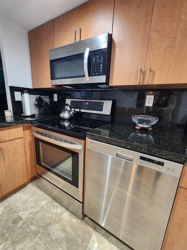 kitchen featuring decorative backsplash, stainless steel appliances, dark stone countertops, and light tile patterned floors