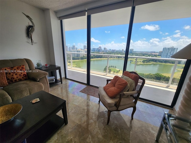 tiled living room featuring a water view, expansive windows, and a textured ceiling