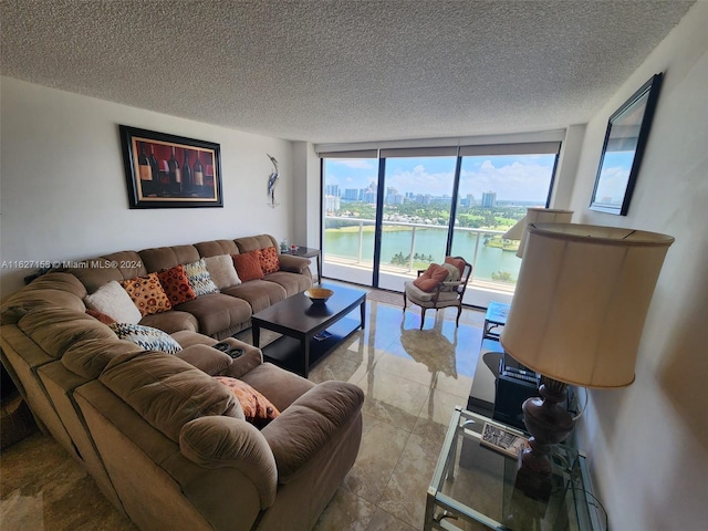 living room featuring a wall of windows, a water view, a textured ceiling, and light tile patterned floors