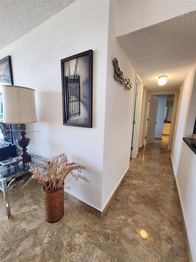 hallway featuring dark tile patterned floors and a textured ceiling