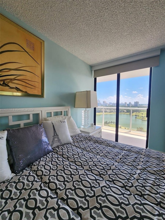 unfurnished bedroom featuring a textured ceiling, a water view, and carpet