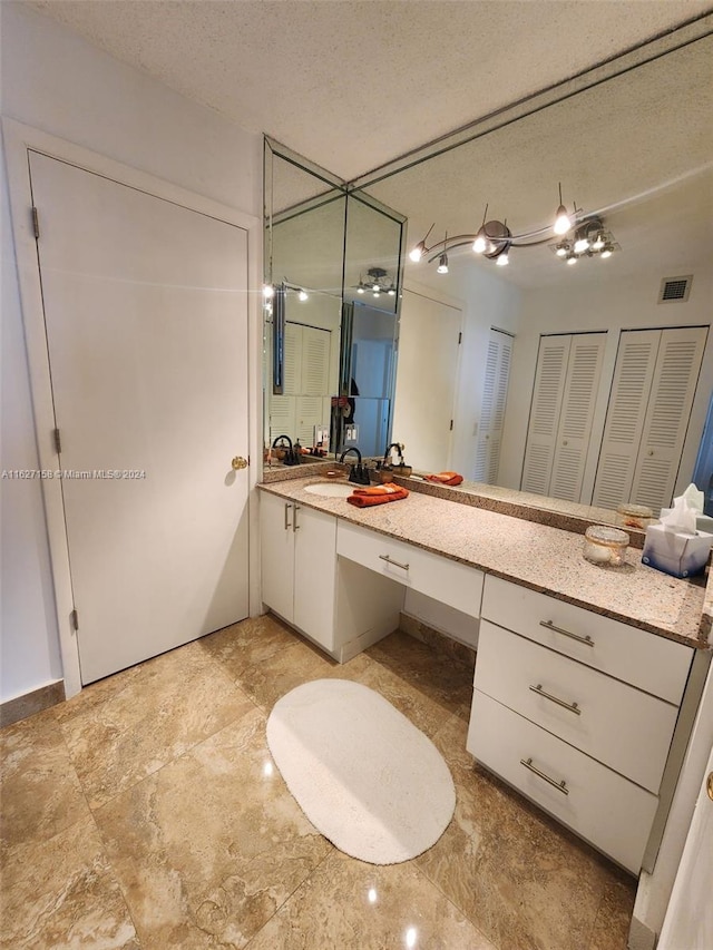 bathroom featuring tile patterned flooring, vanity, and a textured ceiling