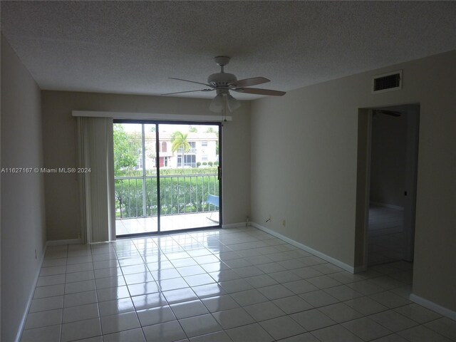 tiled empty room with a textured ceiling and ceiling fan