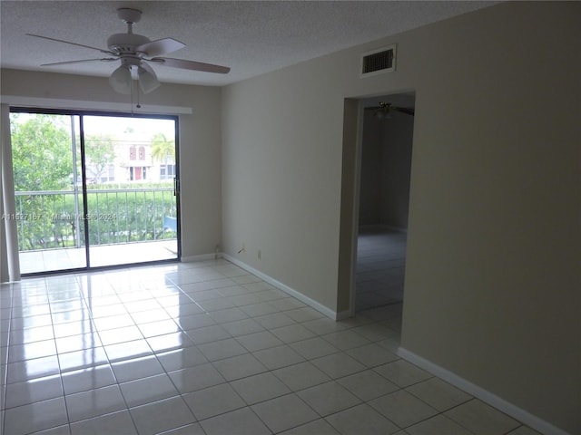 empty room featuring light tile patterned floors, baseboards, visible vents, ceiling fan, and a textured ceiling