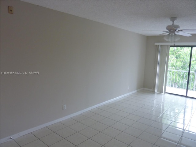 empty room with a ceiling fan, a textured ceiling, baseboards, and light tile patterned floors