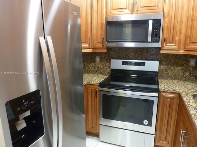 kitchen featuring appliances with stainless steel finishes, brown cabinetry, and light stone counters