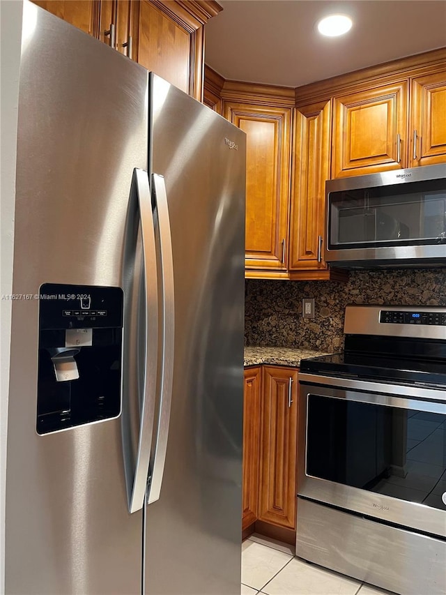 kitchen with appliances with stainless steel finishes, light tile patterned floors, decorative backsplash, and light stone counters