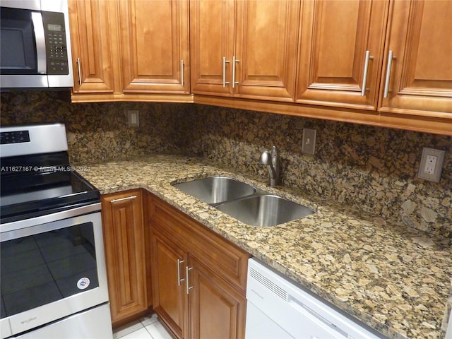 kitchen featuring stone counters, appliances with stainless steel finishes, backsplash, and sink