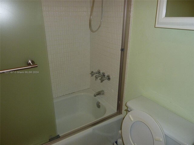 bathroom featuring toilet and bath / shower combo with glass door