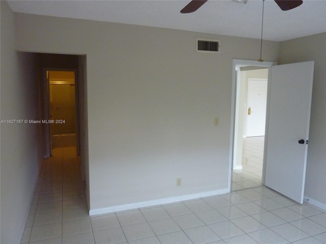 spare room featuring light tile patterned floors, baseboards, visible vents, and a ceiling fan