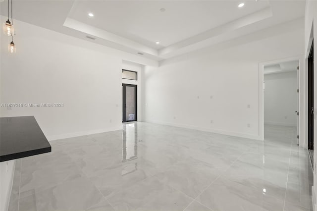 tiled empty room featuring a tray ceiling