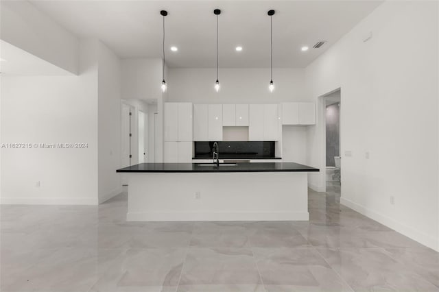 kitchen featuring white cabinetry, tasteful backsplash, light tile patterned floors, a kitchen island with sink, and hanging light fixtures