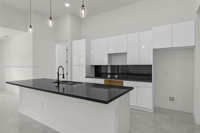 kitchen featuring sink, hanging light fixtures, an island with sink, light tile patterned flooring, and white cabinetry