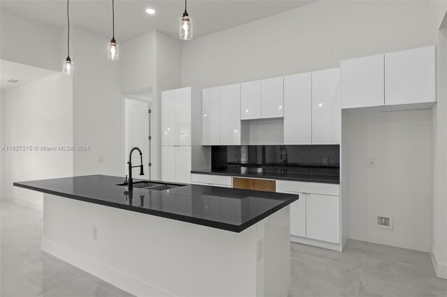 kitchen with pendant lighting, sink, a center island with sink, and white cabinets