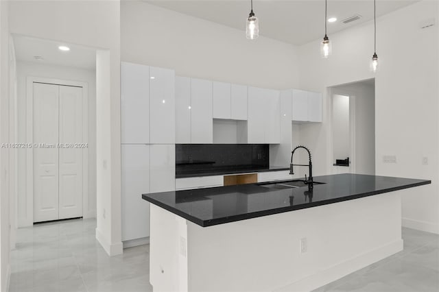 kitchen with sink, white cabinetry, light tile patterned floors, and an island with sink