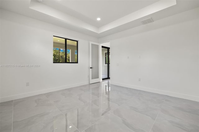 spare room with a raised ceiling and light tile patterned floors