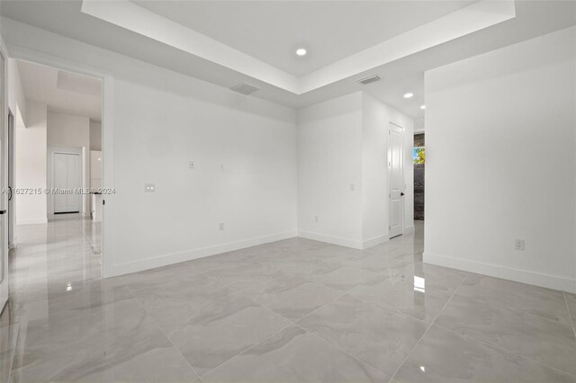 spare room featuring light tile patterned floors and a tray ceiling