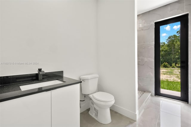 bathroom featuring tile patterned floors, toilet, vanity, and a tile shower