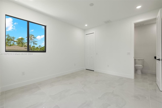 interior space with ensuite bathroom, a closet, and light tile patterned floors