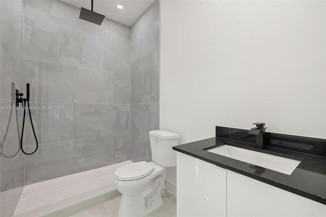 bathroom featuring tile patterned floors, toilet, vanity, and a tile shower