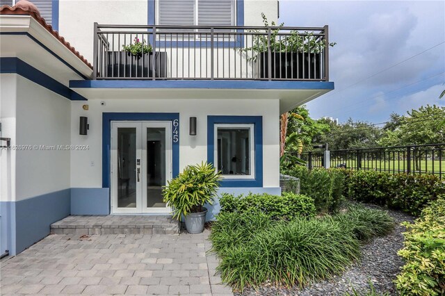 entrance to property featuring a balcony and french doors