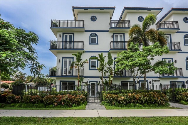 645 NE 9th Ave, Fort Lauderdale, FL 33304 - view of front of property with a balcony, french doors, a fenced front yard, stucco siding, and a gate