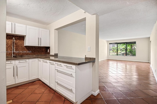 kitchen featuring backsplash, dark tile patterned flooring, sink, and white cabinets