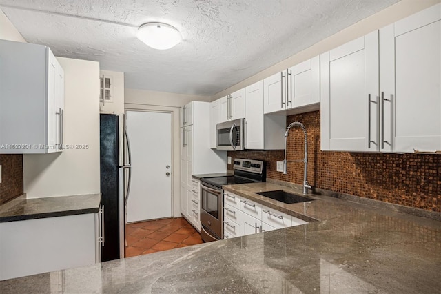 kitchen with tasteful backsplash, appliances with stainless steel finishes, sink, and white cabinets