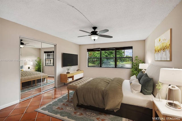 bedroom with tile patterned flooring, ceiling fan, a closet, and a textured ceiling