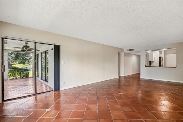 empty room with ceiling fan, tile patterned floors, and a textured ceiling