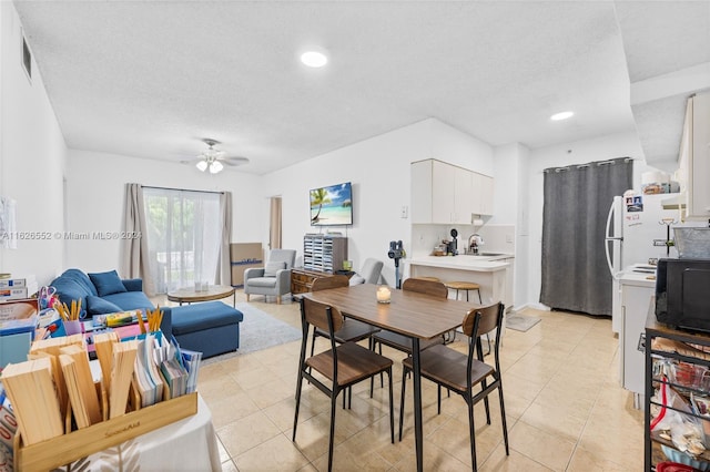 dining space with light tile patterned floors, ceiling fan, a textured ceiling, and sink