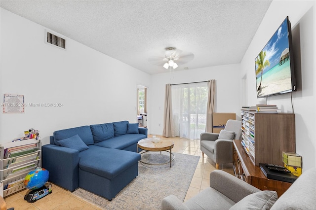 living room with ceiling fan, light tile patterned flooring, and a textured ceiling