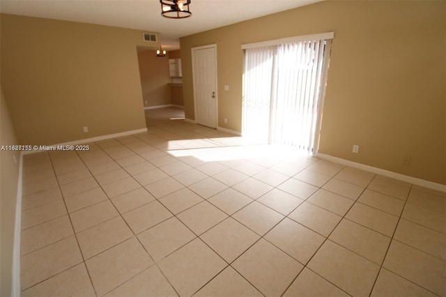 spare room featuring light tile patterned floors and a chandelier