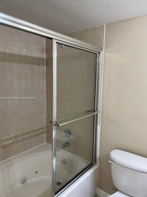 bathroom featuring a textured ceiling, toilet, and enclosed tub / shower combo