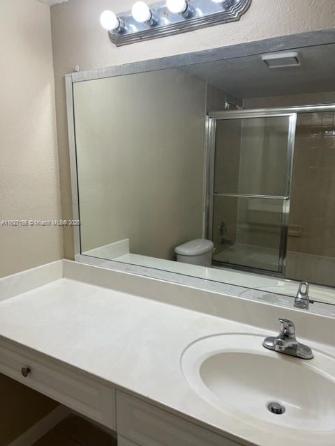 bathroom with vanity, toilet, and a shower with shower door