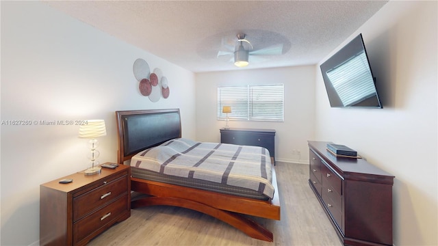 bedroom with ceiling fan, light hardwood / wood-style floors, and a textured ceiling